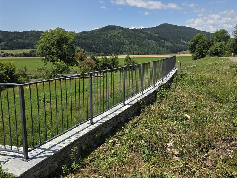 Stabzaun auf einer Natursteinmauer