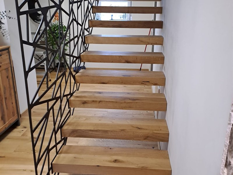 Innentreppe mit Eichenstufen und geometrischem Stahlgeländer