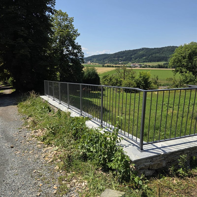 Senkrechtstabzaun auf einer Mauer entlang eines Weges