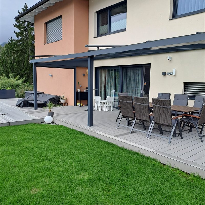 Terrassenüberdachung aus Stahl über einer Sitzgruppe