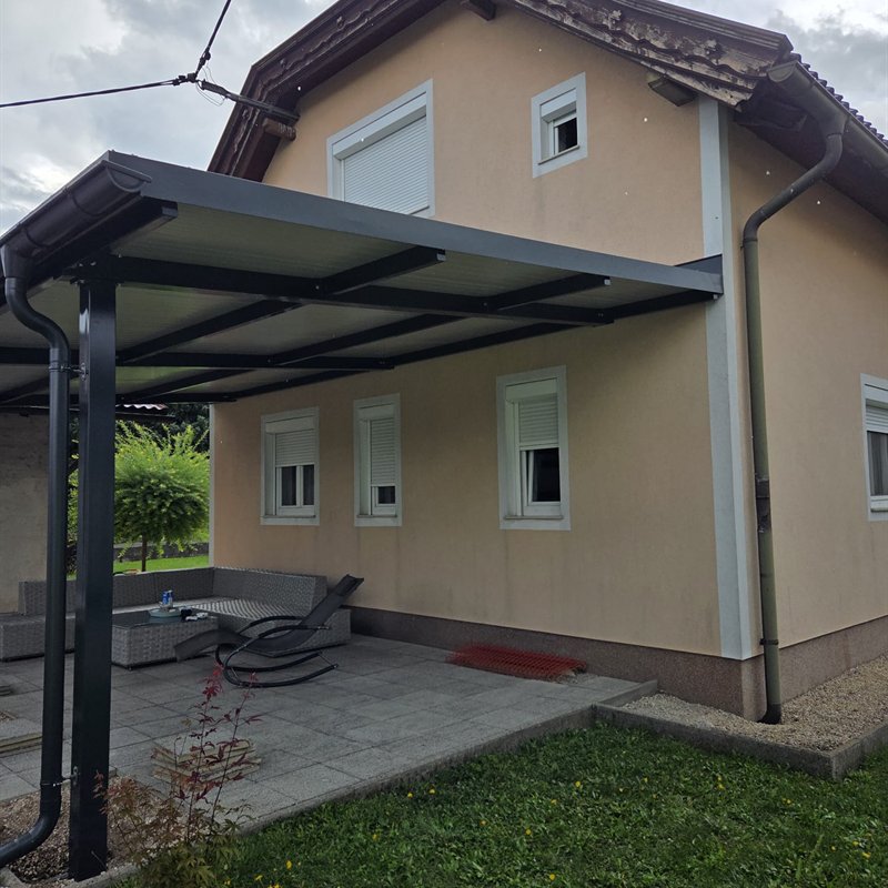 Schlichte Terrassenüberdachung auf Stützen an einem Wohnhaus